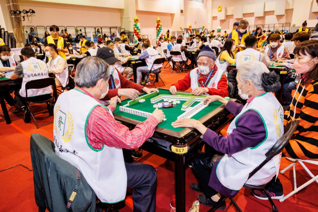 ▲第一屆全國慈善公益盃麻將大賽總決賽，來自全台各地共有284人、71桌同時開打，其中最年長的選手是100歲人瑞鄧奮力（戴毛帽者），儘管行動不便坐著輪椅，但手上動作可是非常靈活。