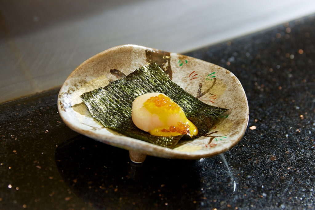 圖說_HAYASE日本料理鐵板燒都會精選套餐菜色中的北海道干貝酒盜醬是選用北海道生食等級干貝搭配以鹽醃漬鰹魚內臟發酵製作的酒盜醬，再加上鮭魚卵，與日本酒非常契合。